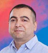 A head shot of Eric Sanchez against a blue and orange background.
