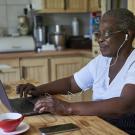 senior woman sitting at kitchen table in front of laptop