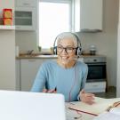 senior woman with headphones on sitting at laptop