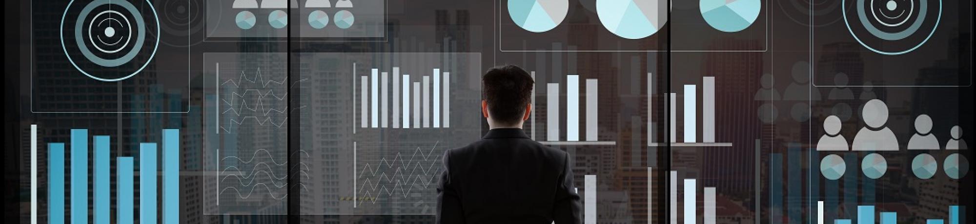 Guy standing in front of Business Analysis Graphs
